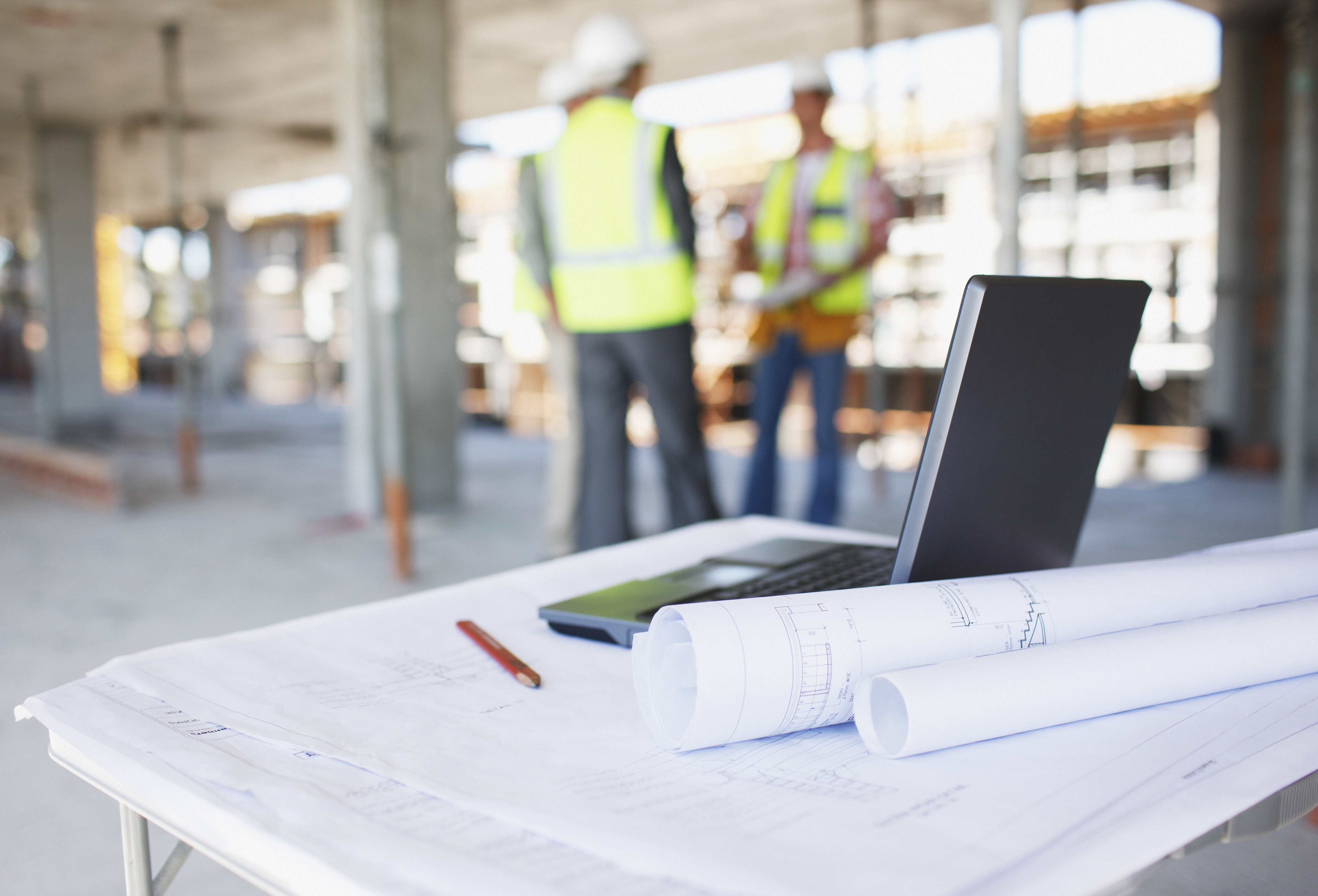 table with laptop and contractors in background